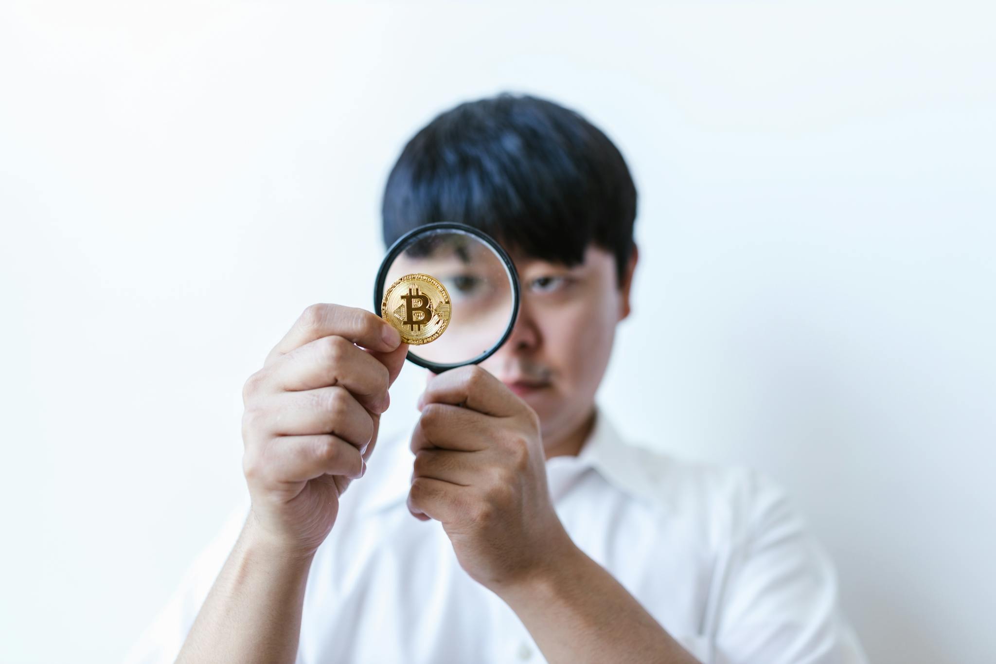 A Man Looking at a Coin Through a Magnifying Glass